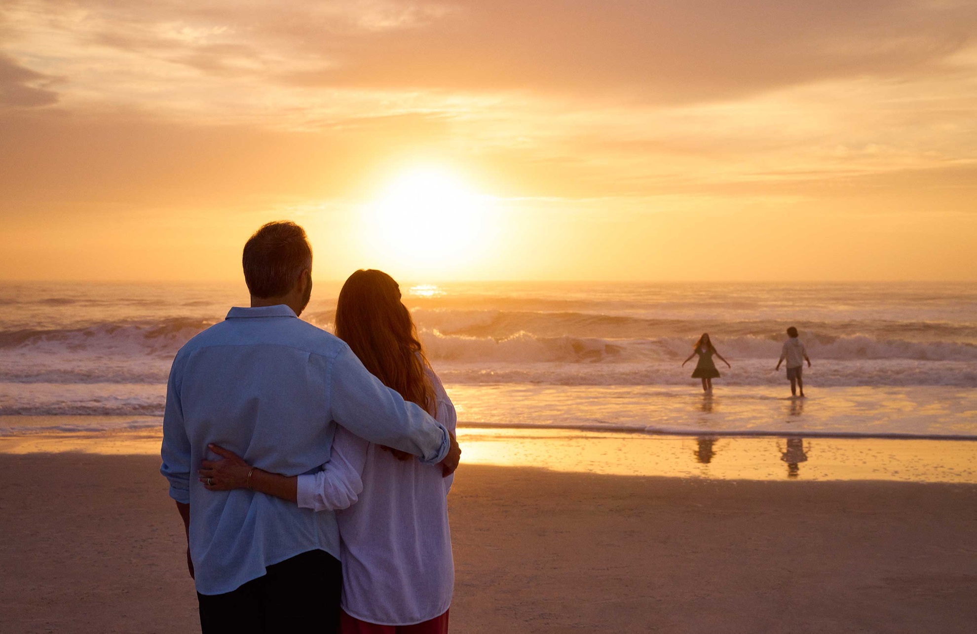 Couple looking at the sunset over the ocean.