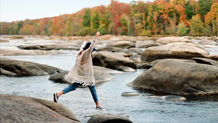 Girl jumping across rocks in a river