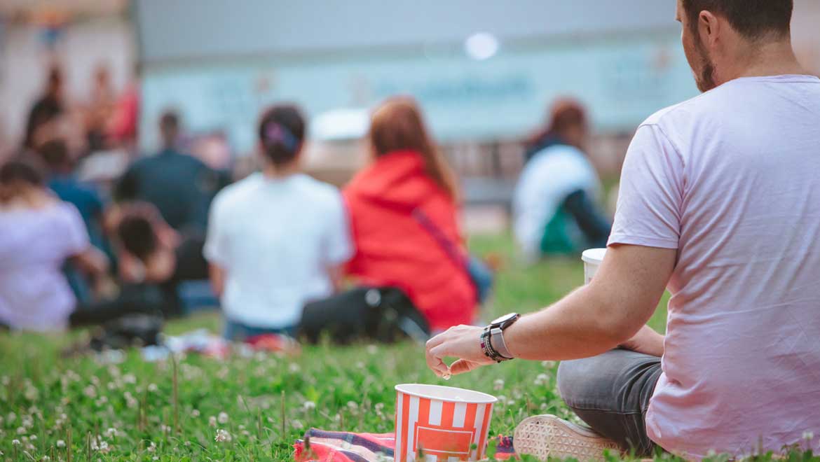 Man eating popcorn at outdoor movie.