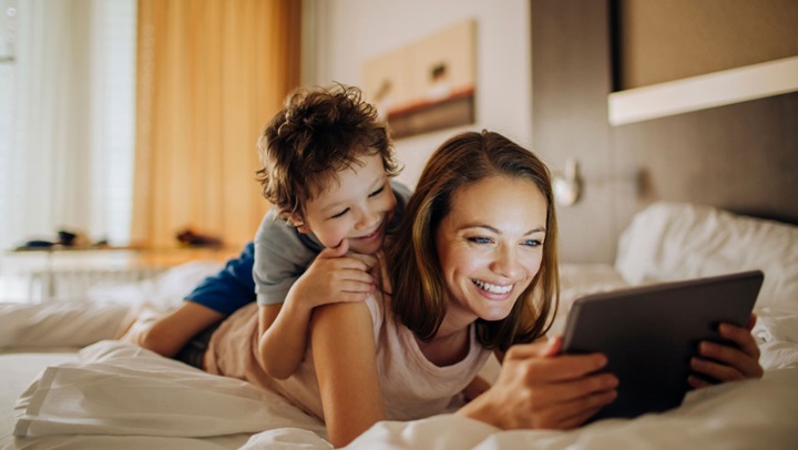 Mother and son looking at tablet on bed