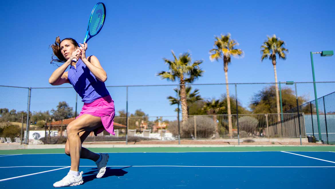 Woman ready to hit a tennis ball with racket.