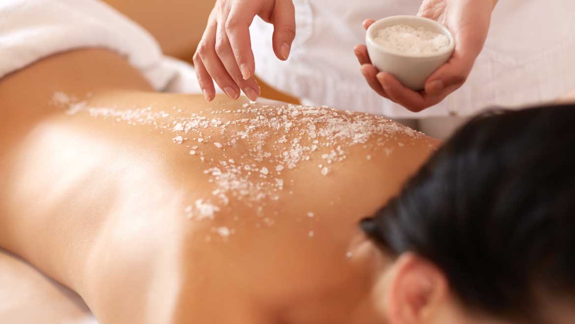 Woman receiving a salt scrub on her back.