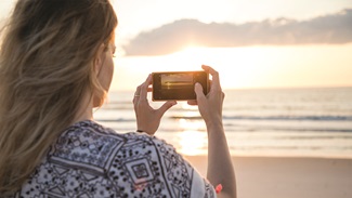 Woman taking picture at sunrise on the beach