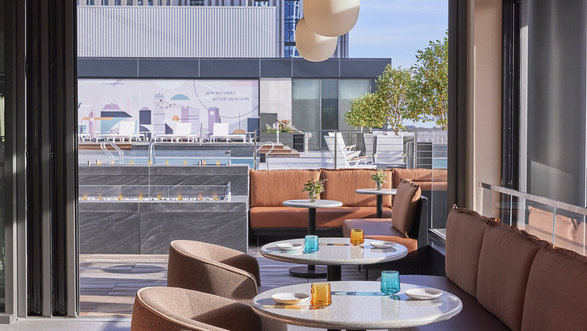 The accordion windows in Lifted Pool Bar open up to the rooftop pool and terrace for alfresco dining - Omni Boston Hotel at the Seaport