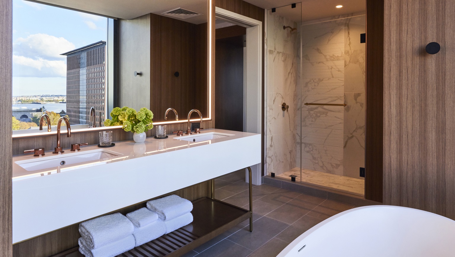 Junior King Suites boast spacious bathrooms with elegant finishes, a walk-in shower and soaking tub - Omni Boston Hotel at the Seaport