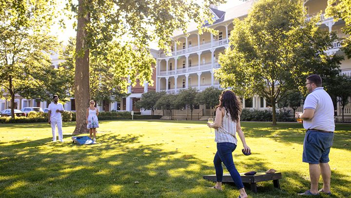 Guests playing corn hole on lawn.