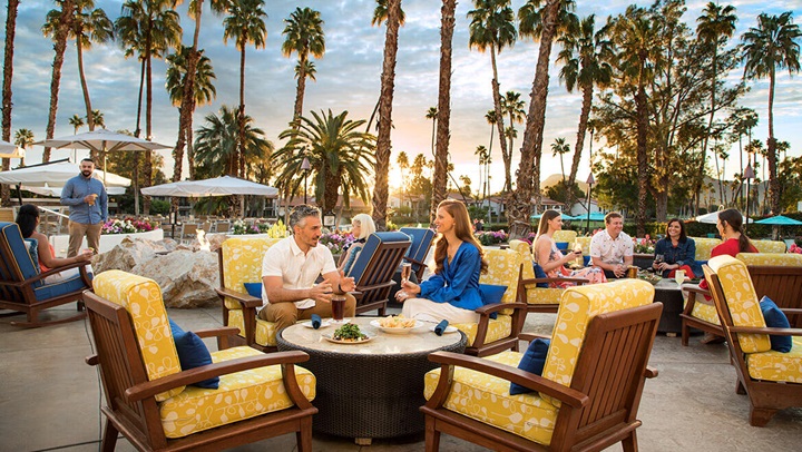 Guests enjoying dinner on a patio at sunset. 