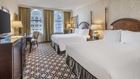 Two queen beds in room with large windows.