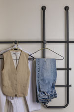 Clothes on hangers shown on sculptural hanging bars