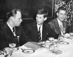 John F. Kennedy and two men at a table